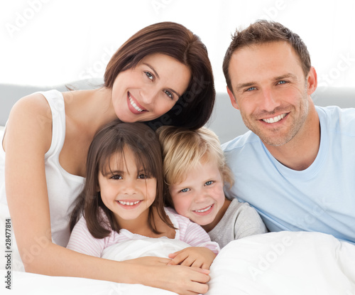 Photo: Lovely family sitting together on the bed Lovely family sitting together on the bed