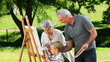 Young boy painting a canvas with grandparents