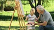 Young child painting a canvas with grandfather