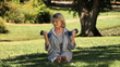 Elderly woman working her muscles with dumbbells sitting on the grass