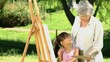 Young girl painting a canvas with grandmother