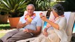 Video: Aged couple toasting with cocktails on deckchairs Aged couple toasting with cocktails on deckchairs