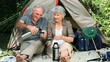 Aged couple drinking coffee sitting near a tent