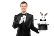 A magician in a black suit holding a top hat with a rabbit in it A magician in a black suit holding a top hat with a rabbit in it