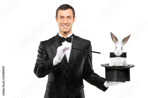 Photo: A magician in a black suit holding a top hat with a rabbit in it A magician in a black suit holding a top hat with a rabbit in it