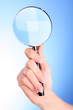 Woman hand with magnifier on blue background