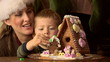 Mother and toddler son with gingerbread house at Christmas Mother and toddler son with gingerbread house at Christmas