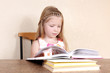Little girl reading book in the kitchen against yellow wall at h