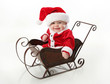 Photo: Smiling santa baby sitting in a sleigh Smiling santa baby sitting in a sleigh