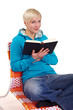 Reading a black book on armchair