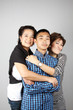 Mother and auntie hugging their straight face teenage boy.