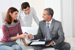 Photo: Young couple sigining renting contract with real estate agent Young couple sigining renting contract with real estate agent