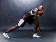 Confident young man playing basketball against grunge background