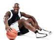 Smiling young sportrsman sitting with basketball