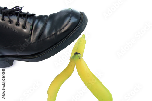Photo: Business boot to step on a banana skin on a white Business boot to step on a banana skin on a white
