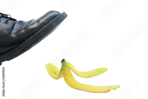 Photo: Business boot to step on a banana skin on a white Business boot to step on a banana skin on a white