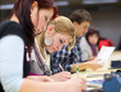 pretty female college student sitting in a classroom full of stu pretty female college student sitting in a classroom full of stu