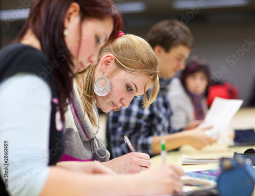 Photo: pretty female college student sitting in a classroom full of stu pretty female college student sitting in a classroom full of stu