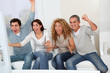 Group of friends sitting in sofa watching sport game on tv