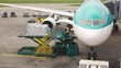 airplane standing at airstrip is loaded with goods by workers