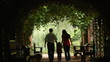 silhouettes of parents with kid who walks in plant tunnel