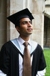 A portrait of a young Indian guy in a graduation gown.