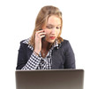 Young business woman on the phone while looking at her laptop