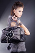 Beauty Brünette blickt cool mit Handtasche in die Ferne, hoch