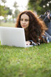 Foto: Woman working on her laptop in a park. Woman working on her laptop in a park.