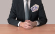 Man at desk with money, UK pounds, in pocket, hands clasped Man at desk with money, UK pounds, in pocket, hands clasped