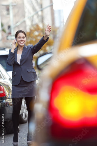 Photo: Young Woman on Cell Phone Hailing a Yellow Taxi Cab Young Woman on Cell Phone Hailing a Yellow Taxi Cab