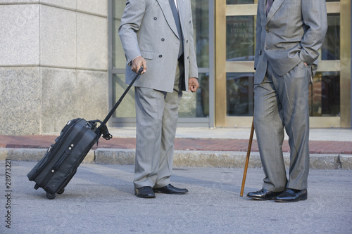 Photo: Two well dressed businessmen talking in front of office Two well dressed businessmen talking in front of office