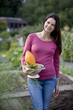 A young woman holding a colander full of vegetables