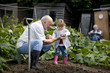 A grandfather showing a worm to his granddaughter
