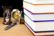 pile of books, pen and hourglass on black pile of books, pen and hourglass on black