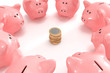 Group of piggy banks looking at a pile of coins