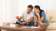 Couple calculating their domesitc bills on their sofa