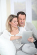 Photo: Couple sitting in sofa with electronic tab Couple sitting in sofa with electronic tab