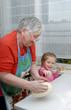 Grandmother and granddaughter knead the dough