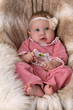 Sweet beautiful baby girl lying in a fur seat
