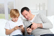Photo: Father and son playing video game at home Father and son playing video game at home