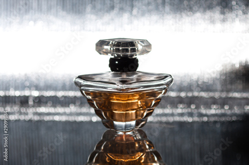 Photo: Perfume bottle with reflection on silver Perfume bottle with reflection on silver