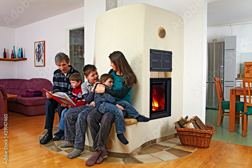 Foto: family sitting on the bench of a masonry stove 01 family sitting on the bench of a masonry stove 01