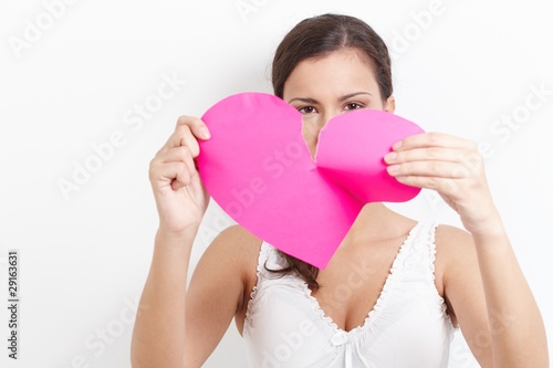 Foto: Young woman pulling paper heart to pieces Young woman pulling paper heart to pieces