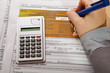 Woman hand filling income tax forms with calculator