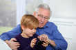 Photo: Old man with little boy playing video game on telephone Old man with little boy playing video game on telephone