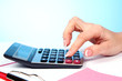Fingers and calculator on blue background