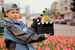 boy with cinema clapper board standing on streets