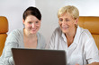 Seniorin und junge Frau sitzen gemeinsam vor dem Notebook 01
