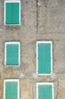 Closed green window shutters on a gray house facade
